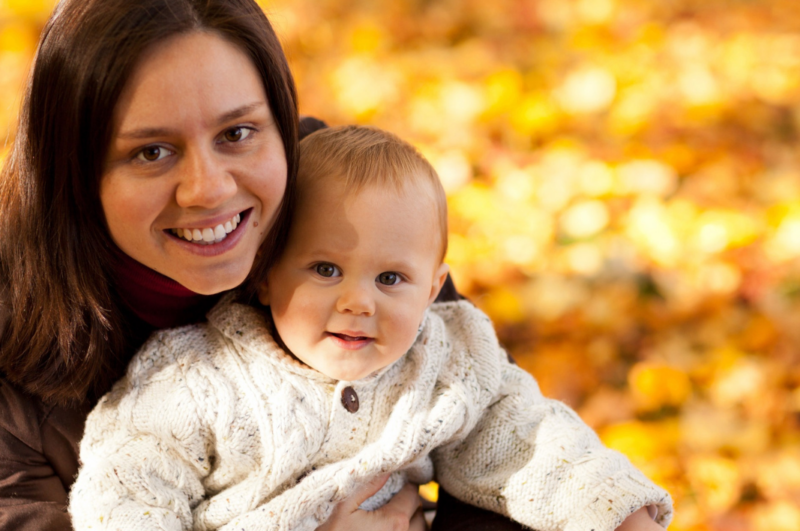 Mother holding baby with fall leaves in the background